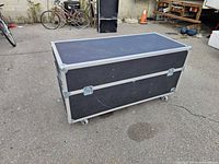 Front view of one black road case showing laminate exterior, aluminum trim, casters