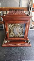 Front view of wooden mantel clock showing dial and decorative trim