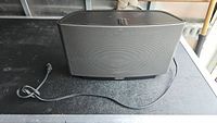 Front view of Sonos speaker with grille and attached power cord