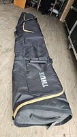 Full view of black Thule rolling ski bag laying flat