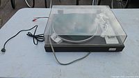 Turntable with dust cover, power and RCA cables visible