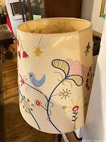 Close view of embroidered drum shade with floral and bird motif