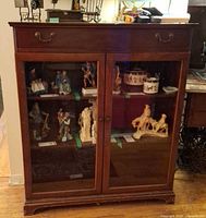 Front view showing glass doors, drawer, interior shelves