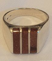 Front view of ring showing three vertical inlay stripes on rectangular face