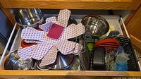 Drawer containing stainless steel bowls, colanders, silicone protectors, utensils