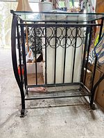 Side view showing wrought iron frame, glass top, lower shelf