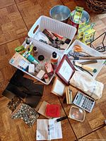 Overhead view of mixed household lot showing bookends, tools, toast stamp packages, calculator, linens and frames