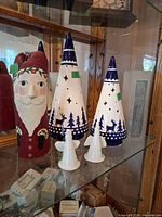 Front view of all items: two ceramic cone trees, two angels, carved wooden Santa