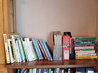 Shelf view showing multiple cookbooks of varied sizes and bindings