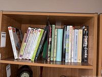 Full shelf of approximately 16–20 cookbooks
