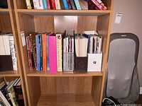 Shelf section with cookbooks, binders, brown plastic file, white mesh holder