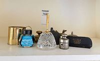 Group shot showing ink bottle, glass inkwell, brass cup, metal weight, pince-nez case, fox figurine and desk bell
