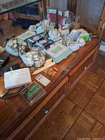 Overview of assorted bulbs, timer, power strip, batteries, tealights on wooden cabinet