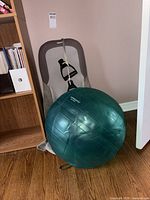 Green Livingarts exercise ball in front of gray massage cushion and black handle