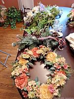 Wreath with extra greenery and evergreen pick on table