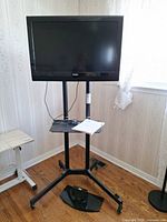 Front view of Haier TV mounted on mobile stand, extra tabletop base visible