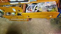 Three timber drawers open showing paint rollers, hardware, cords, locksets