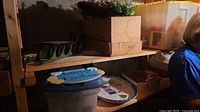 shelved lot showing sled, wreath, cardboard boxes, yellow tote and storage bin