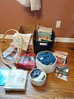 Group shot showing yarn bowls, skeins, hoop, magazines and tote
