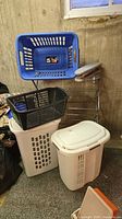 Overall lot showing two baskets stacked on lidded hamper next to drying rack and sleeve board