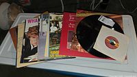 Stack of LPs with Wham!, Lionel Richie, Huey Lewis and the News visible plus loose disc and 45