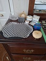 All six items displayed on dresser: cut glass tray, glass basket, small crystal dish, porcelain trinket box, gold-tone frame, metal frame