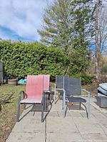 Front view showing red and two gray/black sling chairs on patio