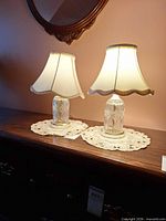 Pair of matching clear glass table lamps with ivory fabric shades on wooden surface