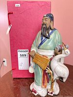 Front view of porcelain Chinese God of Wealth figurine with crane and fan