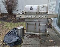 Front view of grill showing dual lids, control panel, doors, side shelves, visible rust and dirt