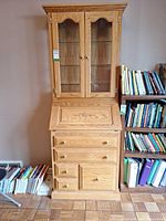 Full view of oak secretary desk with hutch showing drawers and glass doors