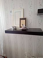 Shelf with framed items, candle, dish, sachet