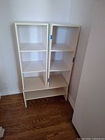 Two vertical and one horizontal white laminate shelves grouped