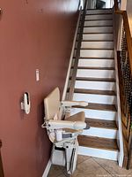 Stairlift installed on straight staircase showing seat, armrests, footrest and rail