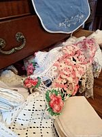 Drawer of assorted linens showing crochet, embroidered pieces, stacks of napkins