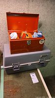 Orange toolbox open on top of gray Holt case