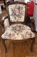 Front view of walnut-tone Louis XV style armchair showing floral tapestry upholstery, nailhead trim, carved frame