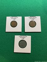 Three Canadian King George V coins in 2×2 holders on green background