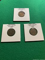 Front view of three Canadian 1-cent coins in holders
