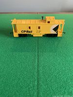 Side view of yellow CP Rail caboose #35644 on green surface