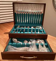 Chest open showing upper and lower tiers filled with flatware