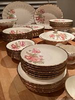Stacked dinner, salad and bread plates with floral design and gold rims