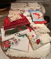 Overview of assorted folded linens on table showing various colors, patterns and lace edges