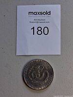 Overall view of single coin beneath lot number tag