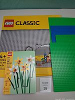 Front of sealed gray baseplate package, sealed daffodils box, three loose baseplates stacked