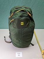 Front view of dark green MEC day backpack showing logo, front zip pocket, yellow zipper pulls