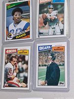 Fronts of the four 1984 Topps NFL cards in sleeves