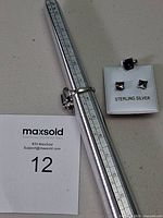 ring on mandrel beside earrings and pendant on card