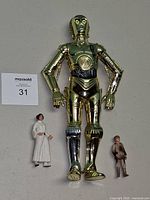 Large metallic C-3PO with two smaller figures beneath