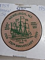 Front of wooden nickel in holder showing design and dates